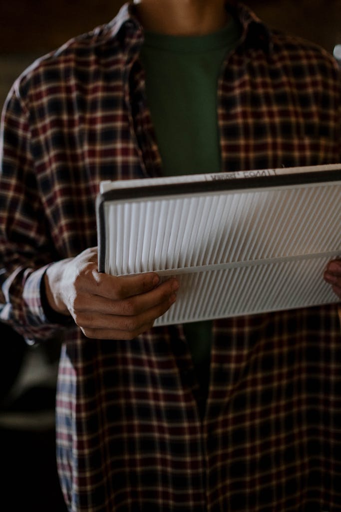 A mechanic holding a car air filter, focusing on automotive maintenance indoors.